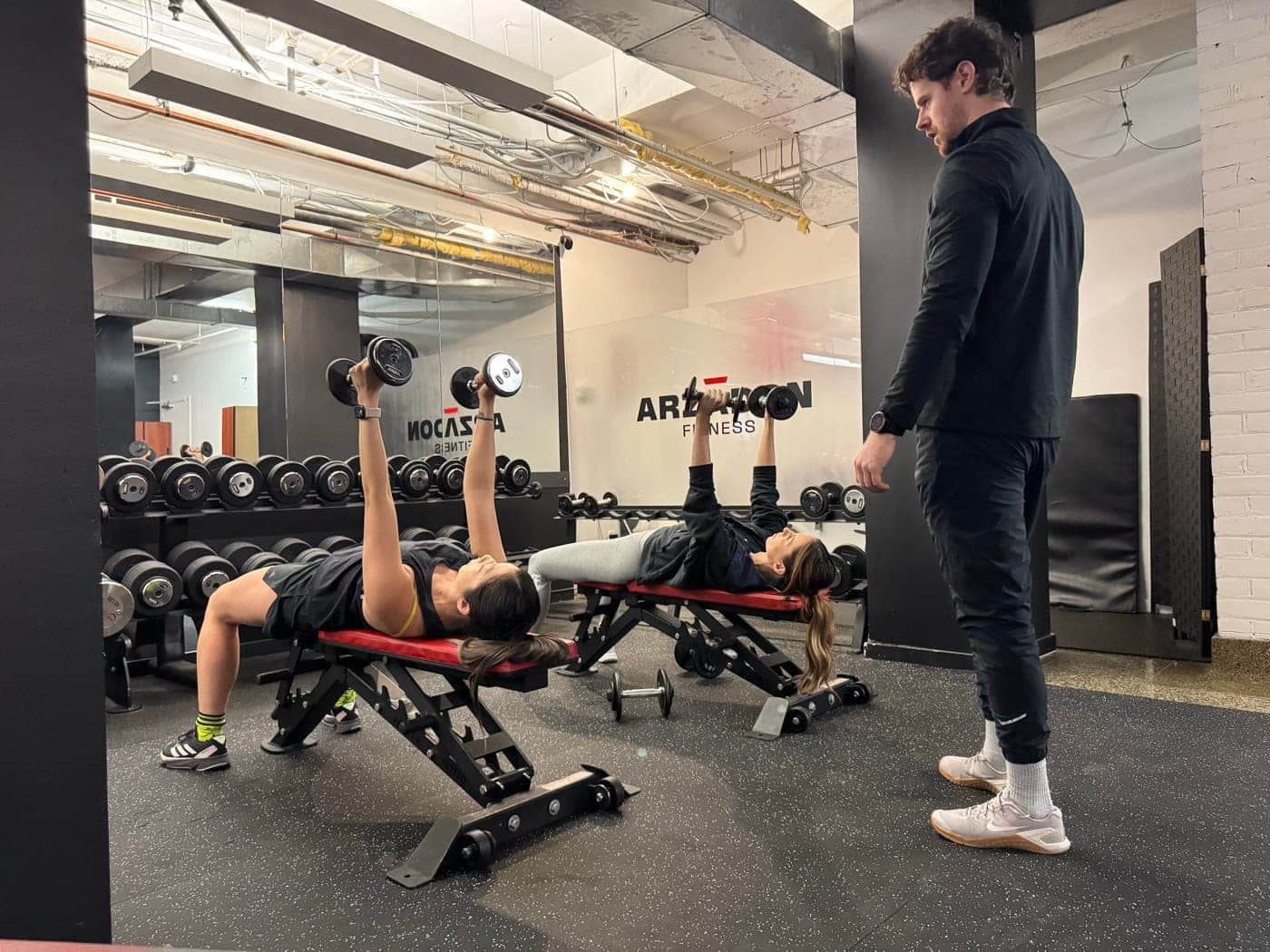 Arzadon trainer coaching client on dumbbell bench press — muscle building personal training Toronto