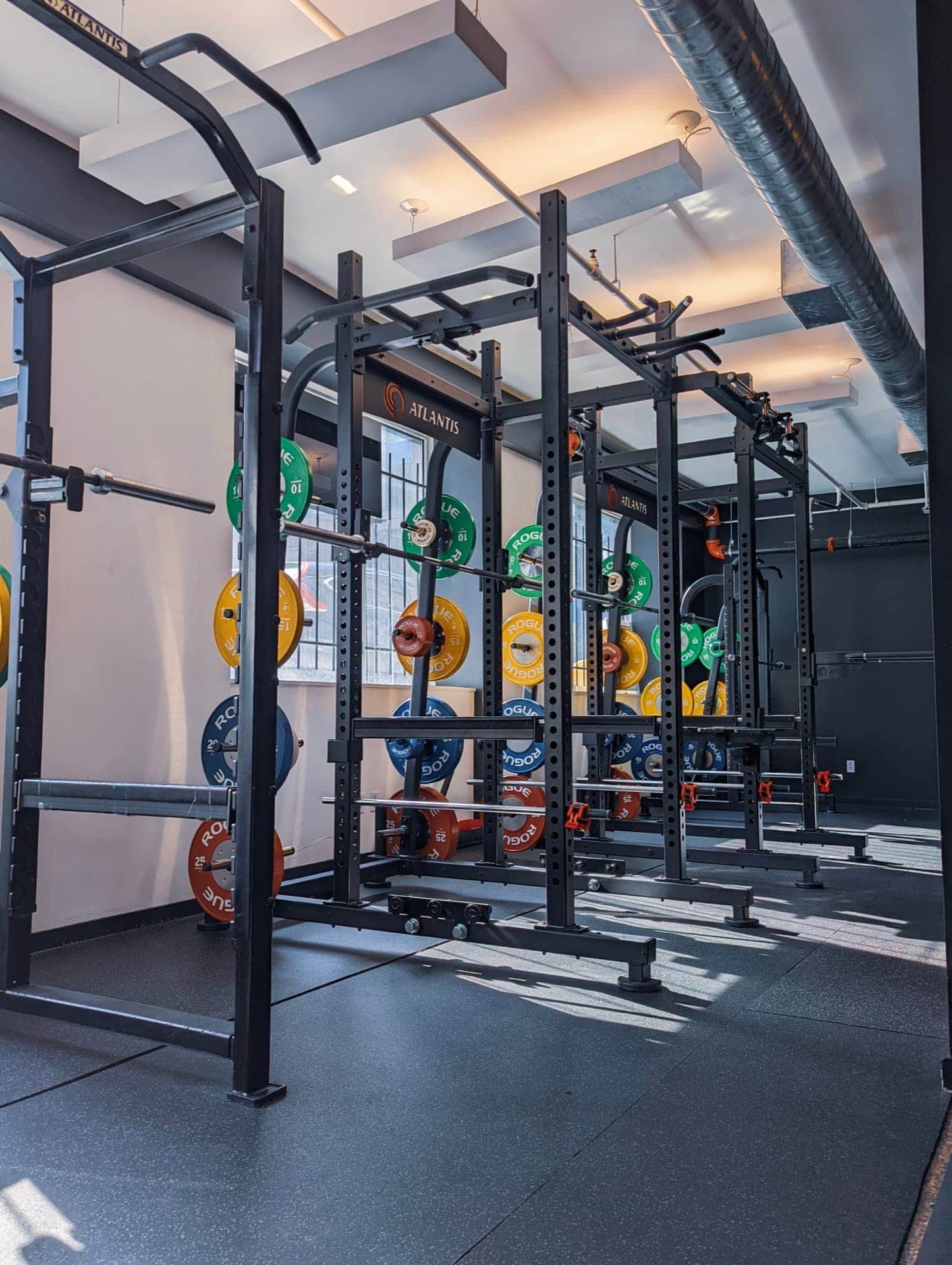 Row of three Atlantis Strength power racks loaded with Rogue bumper plates at Arzadon Fitness gym, King West Toronto