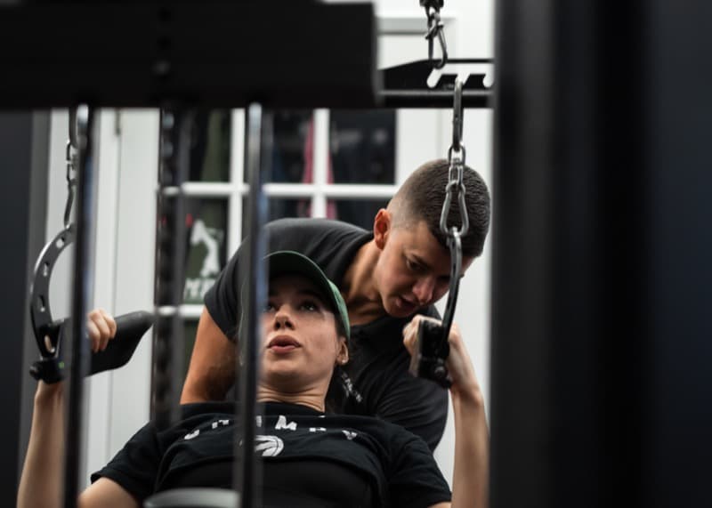 Client performing cable tricep extension with trainer coaching at Arzadon Fitness