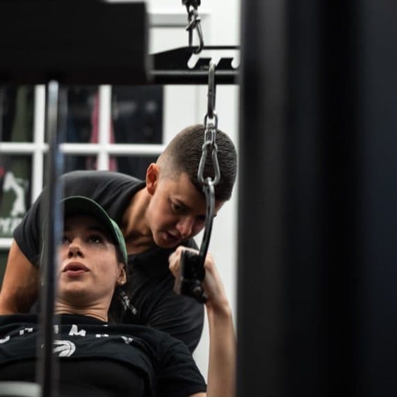 Trainer coaching client through cable tricep extension at Arzadon Fitness Toronto