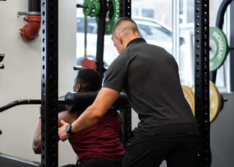 Athletic male client performing barbell squat at Arzadon Fitness King West Toronto sport performance training