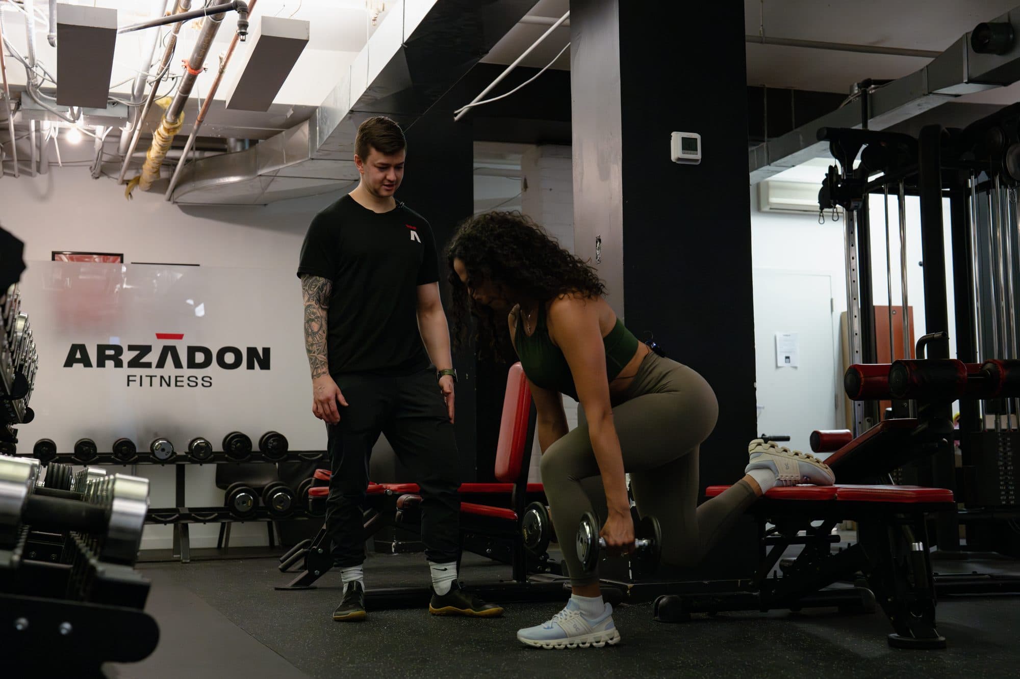 Arzadon Fitness coach guiding a client through single-arm dumbbell row technique during a strength assessment in Downtown Toronto